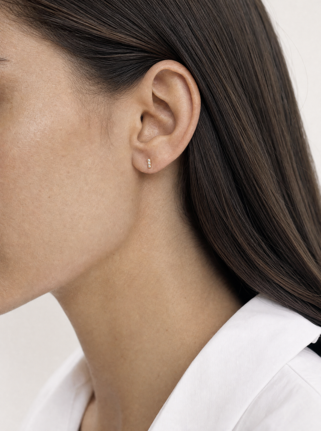 Broquel Barra Triple Micro Oro 10K puesto en oreja — escala real