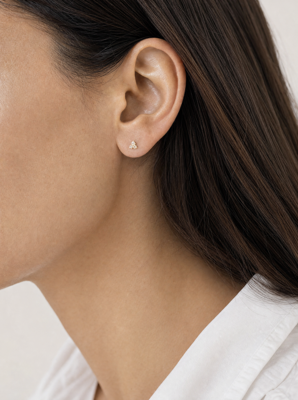 Broquel Tresillo Micro Oro 10K puesto en oreja — escala real