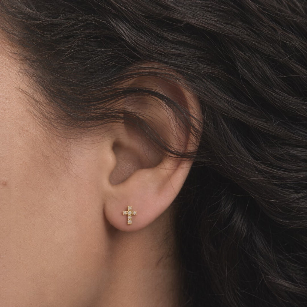 Broquel Cruz Zirconia Oro 10K puesto en la oreja: la modelo se acomoda el cabello.