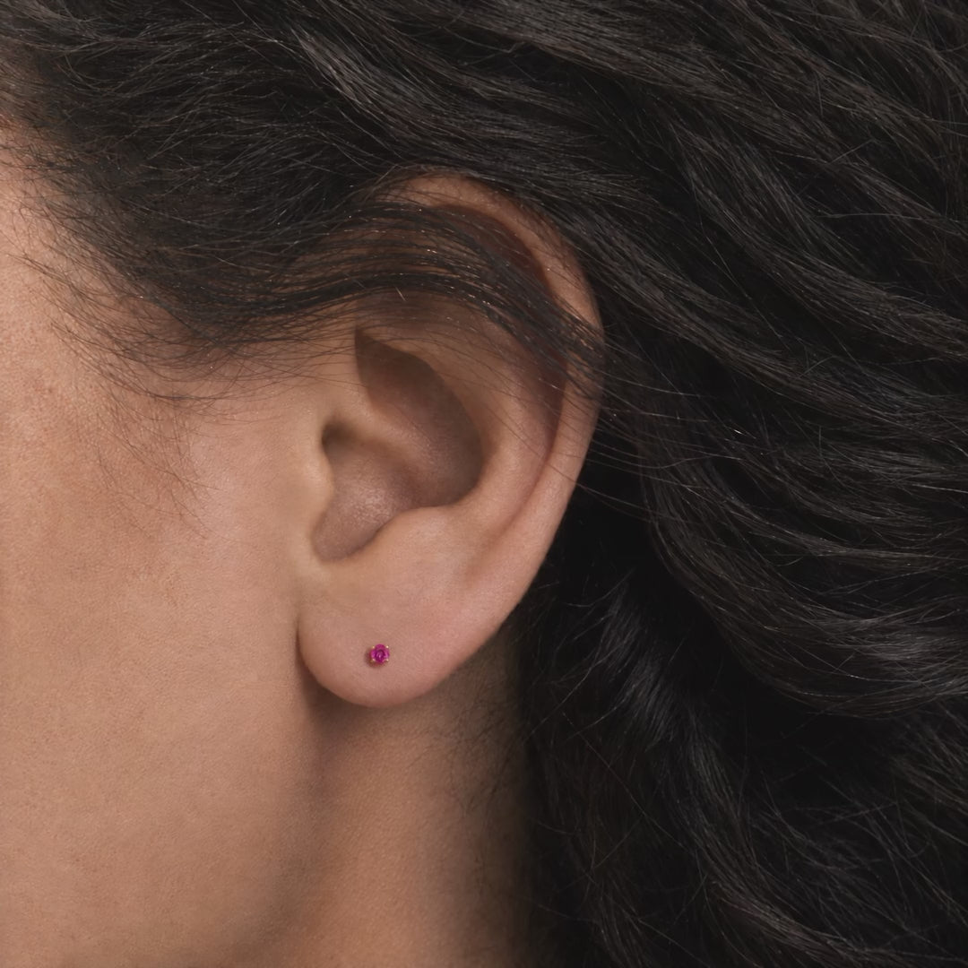 Broquel Solitario Zirconia Magenta 2.25 mm Oro 10K puesto en la oreja: la modelo se acomoda el cabello.