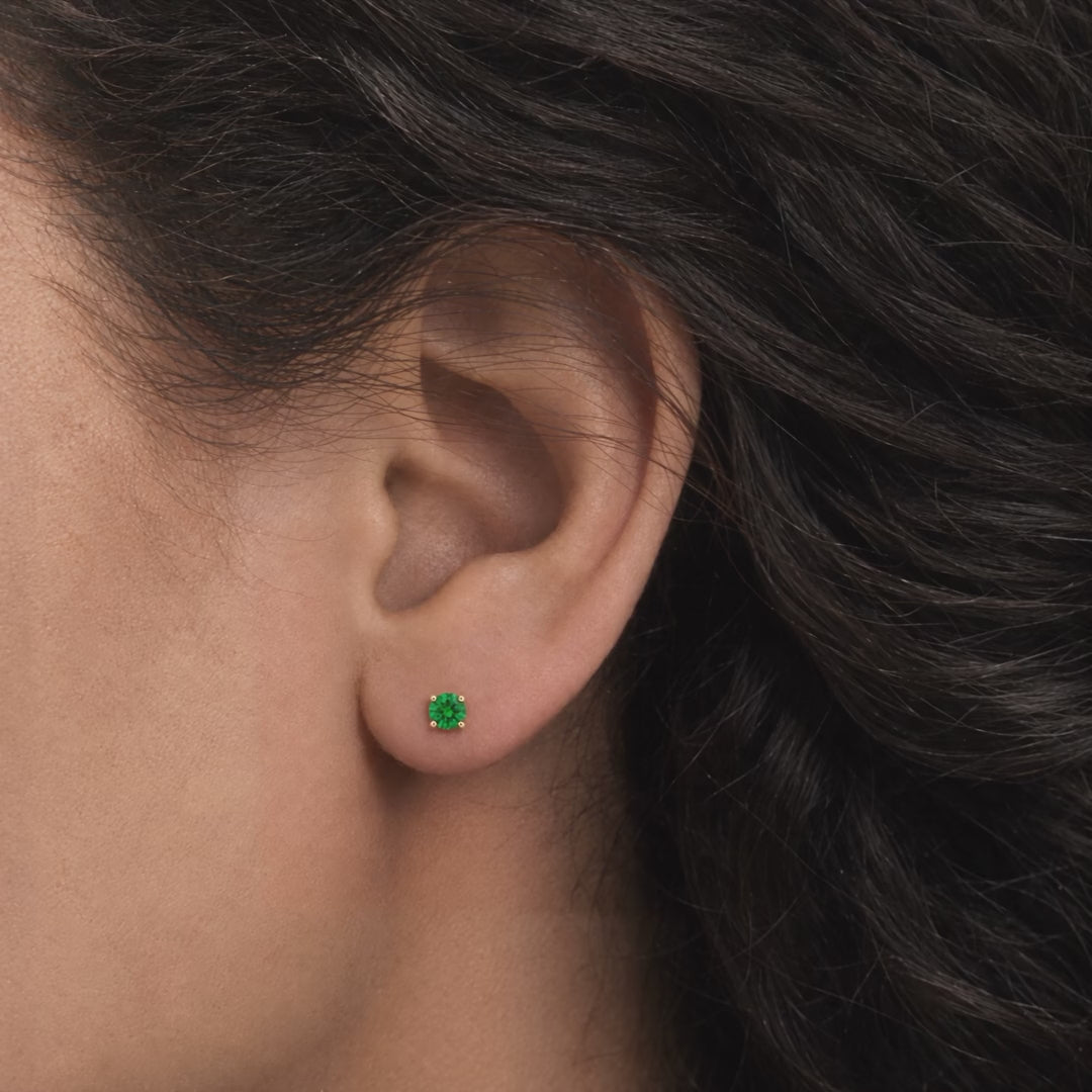 Broquel Solitario Zirconia Verde 4 mm Oro 10K puesto en la oreja: la modelo se acomoda el cabello.