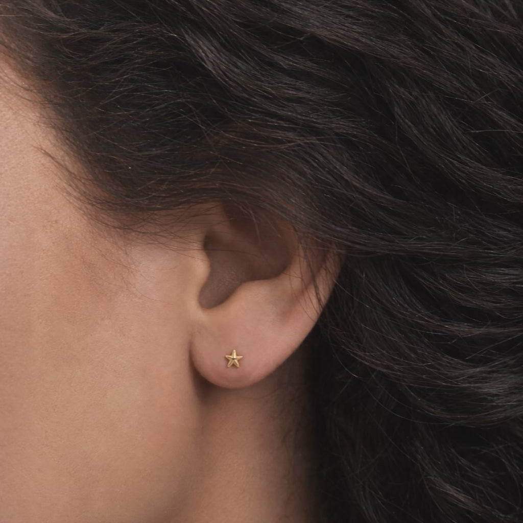 Broquel Estrella de Mar Oro 10K puesto en la oreja: la modelo se acomoda el cabello.