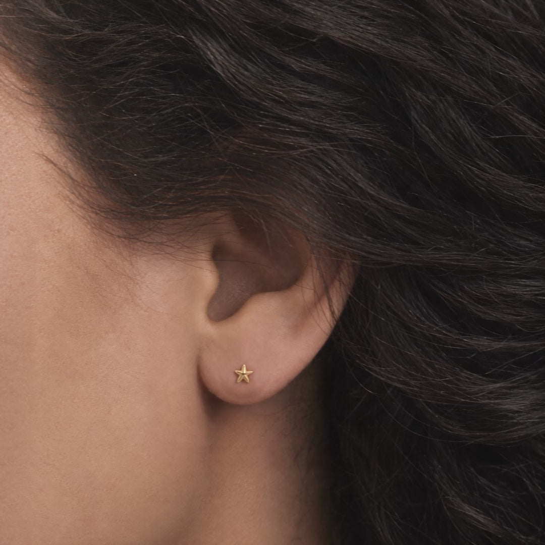 Broquel Estrella de Mar Oro 10K puesto en la oreja: la modelo se acomoda el cabello.