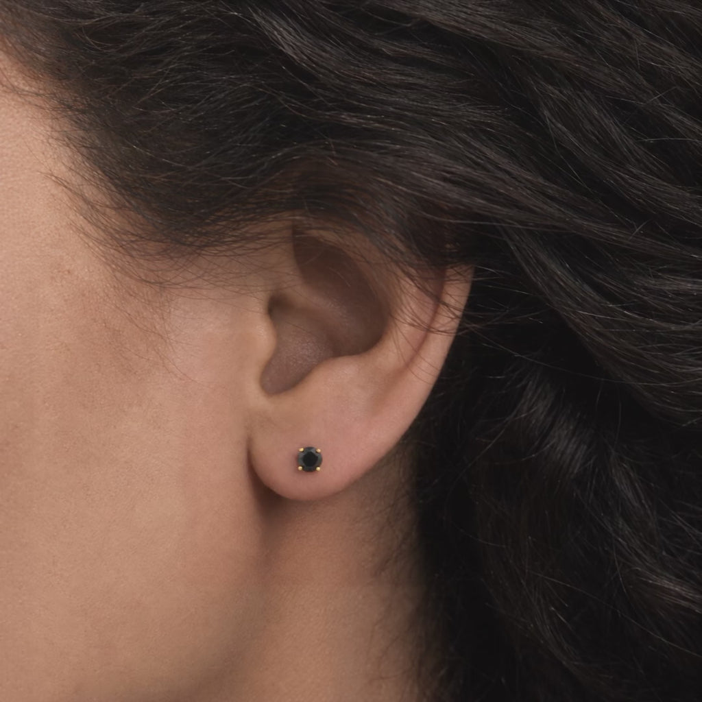 Broquel Solitario Zirconia Negra 4 mm Oro 10K puesto en la oreja: la modelo se acomoda el cabello.