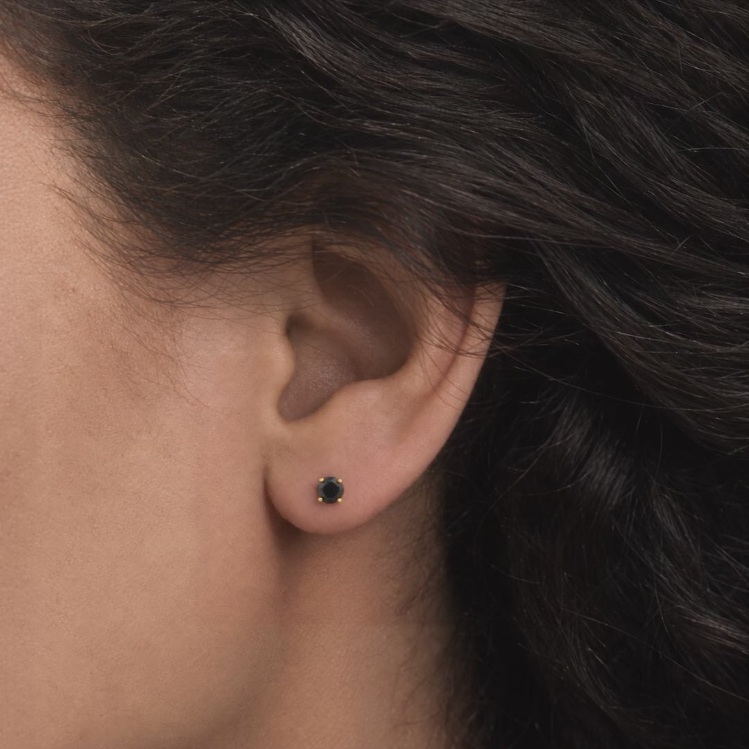 Broquel Solitario Zirconia Negra 4 mm Oro 10K puesto en la oreja: la modelo se acomoda el cabello.