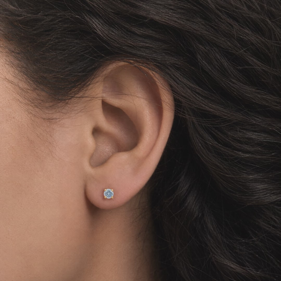 Broquel Solitario Zirconia Aqua 4 mm Oro 10K puesto en la oreja: la modelo se acomoda el cabello.