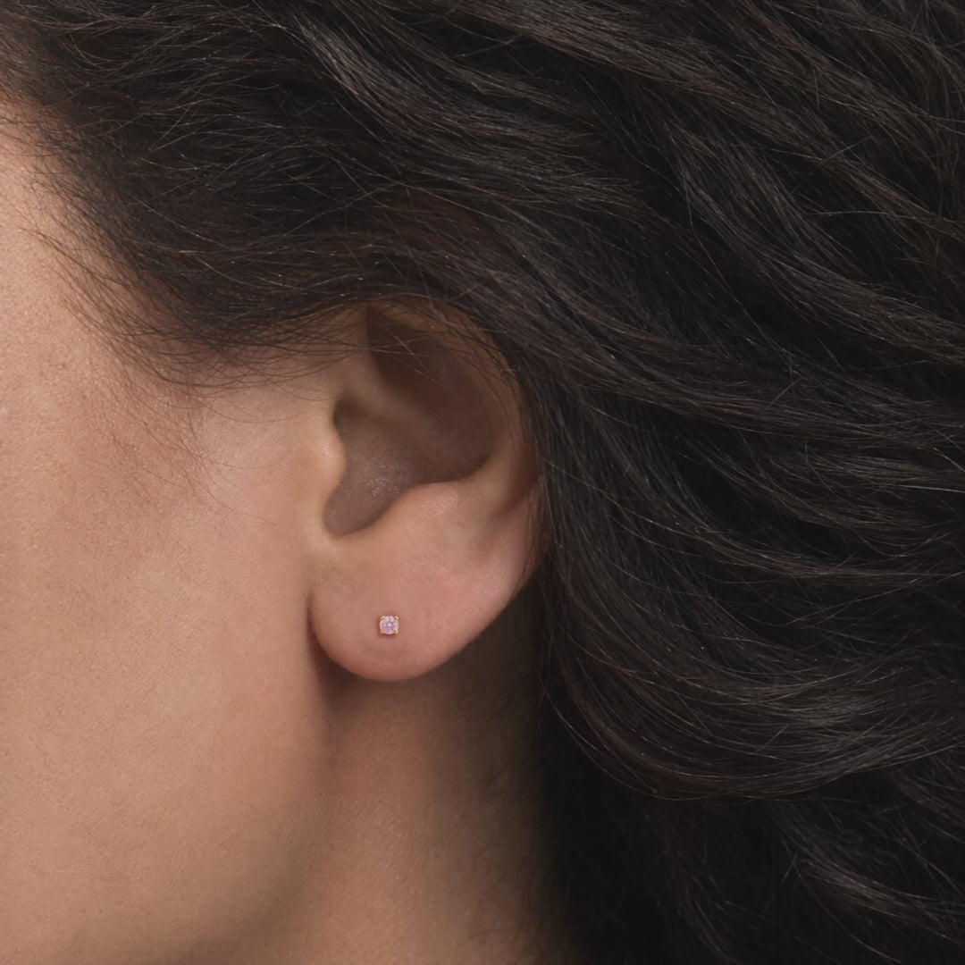 Broquel Solitario Zirconia Rosa 2.25 mm Oro 10K puesto en la oreja: la modelo se acomoda el cabello.