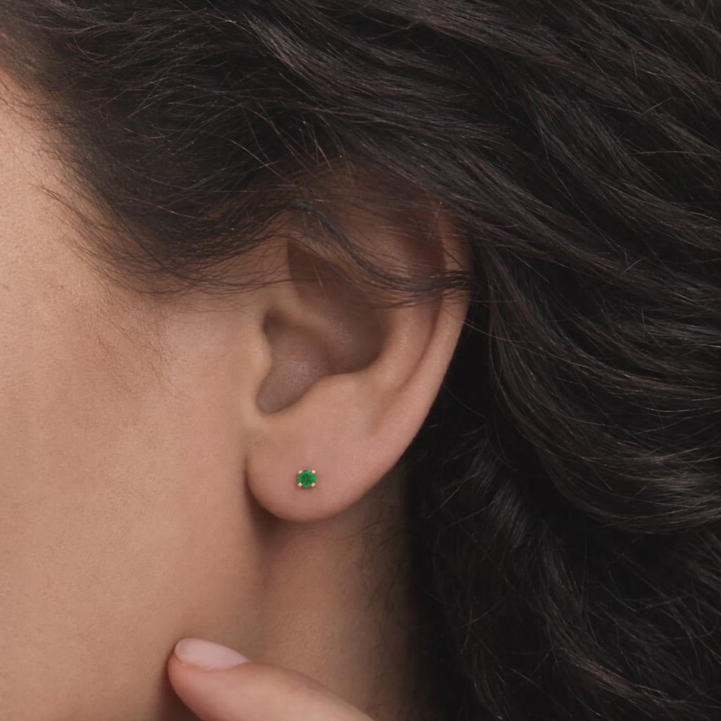 Broquel Solitario Zirconia Verde 3 mm Oro 10K puesto en la oreja: la modelo se acomoda el cabello.