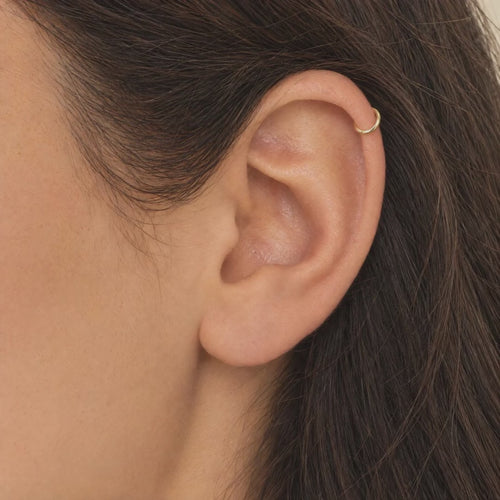 Arracada Lisa 6.6 mm Oro 10K puesta en el hélix: la modelo se acomoda el cabello.