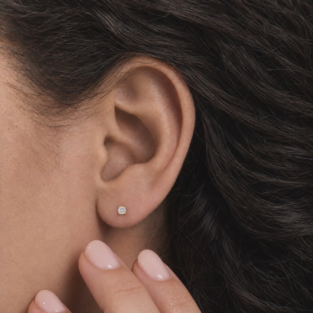 Broquel Solitario Zirconia Blanca 3 mm Oro 10K puesto en la oreja: la modelo se acomoda el cabello.