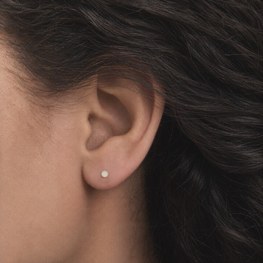 Broquel Solitario Zirconia Tornasol 3 mm Oro 10K puesto en la oreja: la modelo se acomoda el cabello.